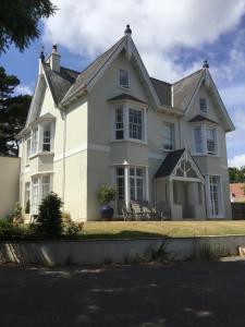 uma grande casa branca com cadeiras em frente em Park House em Budleigh Salterton