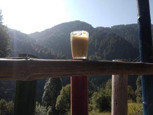 um copo de cerveja sentado numa grade com uma montanha em Ara Camps em McLeod Ganj