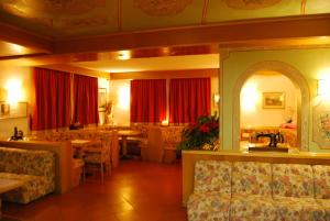 フォルガリーアにあるAlbergo Villa Cristinaのテーブルと椅子、赤いカーテンが備わるレストラン