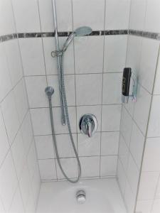 um chuveiro com uma mangueira na casa de banho em A&M Hotel Barsinghausen em Bad Nenndorf