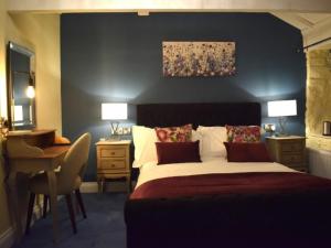 a bedroom with a large bed and a desk and a desk at The Mendip Inn in Binegar