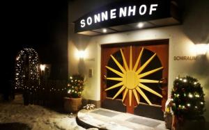 Una puerta de entrada de una empresa con árboles de Navidad en la nieve. en Sonnenhof Walchsee, en Walchsee 17 fotos más