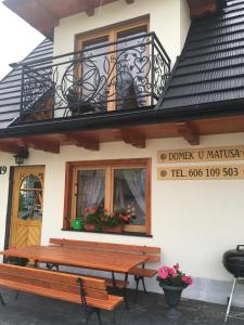 un banco de madera frente a un edificio con balcón en Domek u Matusa, en Gliczarów Górny