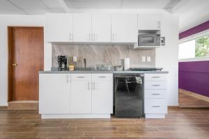 une cuisine avec des armoires blanches et un micro-ondes dans l'établissement Deluxe Loft at Colonia ROMA, à Mexico