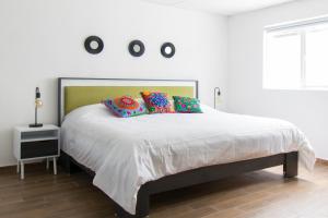 une chambre avec un grand lit blanc avec des oreillers colorés dans l'établissement Deluxe Loft at Colonia ROMA, à Mexico