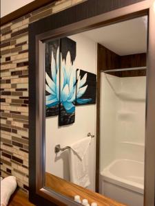 a bathroom mirror with a picture of a blue flower at La Spacieuse Riverstone in Saint Pierre de Broughton