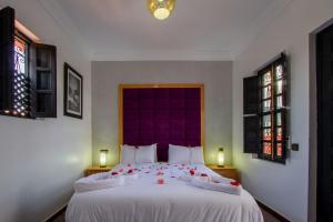 um quarto com uma grande cama branca com cabeceira roxa em Ryad Amiran & Spa em Marraquexe