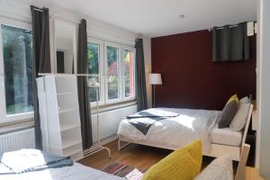 a bedroom with a bed and a chair and windows at The garden flat in Luxembourg