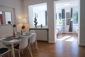 a dining room with a table and white chairs at The garden flat in Luxembourg