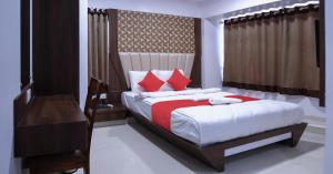 a bedroom with a bed with red and white pillows at Hotel Apple Inn in Navi Mumbai