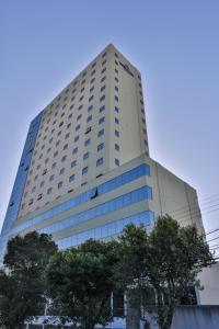 um edifício alto e branco com árvores em frente em Nobile Inn Meridional Cariacica em Cariacica