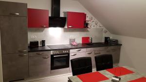 eine Küche mit roten Schränken sowie einem Tisch und Stühlen in der Unterkunft Ferienwohnung im Wonnegau Portugieser-Suite in Flörsheim-Dalsheim