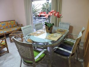 a dining room table with chairs and a glass table with flowers at Condomínio Baia Blanca in Guarujá