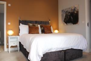 - une chambre dotée d'un grand lit avec des draps blancs et des oreillers bruns dans l'établissement The Old Post Office pretty village 20min from York, à York