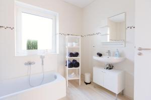 a white bathroom with a tub and a sink at Weserrobbe in Bremerhaven +34 photos