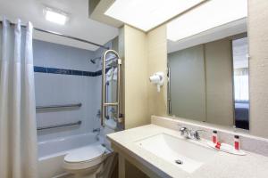 a bathroom with a sink and a toilet and a mirror at Travelodge by Wyndham Deltona in Deltona