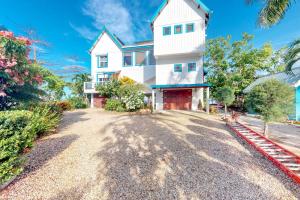 une grande maison blanche dans une allée en gravier dans l'établissement Casa Corazón @ Eddie beach, à Placencia