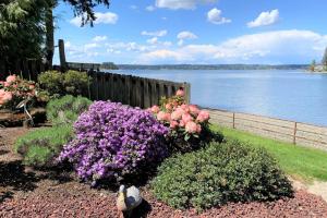 a garden with pink and purple flowers next to the water at The Tides Retreat in Gig Harbor