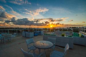 un toit-terrasse avec des tables et des chaises au coucher du soleil dans l'établissement Pousada Marie Claire Flats, à Porto de Galinhas