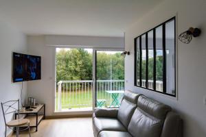 sala de estar con sofá de cuero y puerta corredera de cristal en Les charmes Du Bosquet Parc d'Amour et Nature Parking Privé Sécurisé, en Étretat