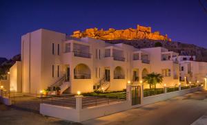 a white building with a mountain in the background at Haraki Bay Hotel and Luxury Apartments in Haraki