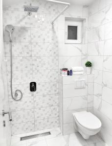 a white bathroom with a shower and a toilet at Apartments Monako in Herceg-Novi