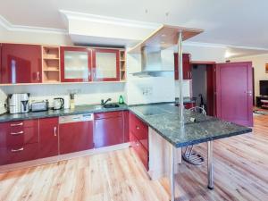 a kitchen with red cabinets and a granite counter top at Penthouse Am Goethepark - Apartments & Suites Weimar in Weimar