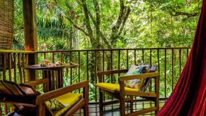 a balcony with two chairs and a tree at Anjali in Ilha de Boipeba