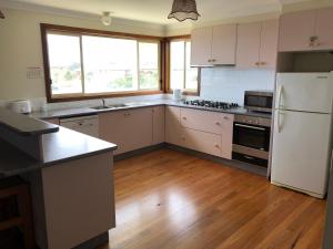 a kitchen with a white refrigerator and a wooden floor at 2 Jocelyn Street. Dalmeny in Dalmeny