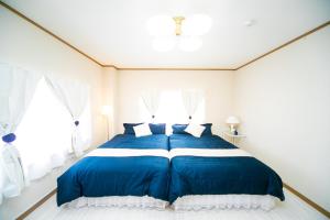 uma grande cama azul num quarto branco com janelas em Awaji Seaside Resort in Shiduki em Awaji