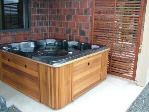 a hot tub in front of a brick wall at Lawrence Townhouse Accommodation in Lawrence