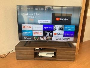 telewizor z płaskim ekranem siedzący na drewnianym stojaku w obiekcie ガナダン中央駅 2f 無料駐車場 w mieście Kagoshima