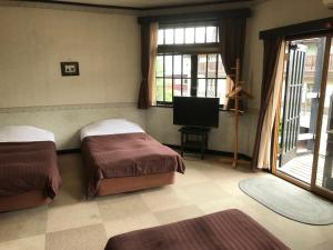 a bedroom with two beds and a flat screen tv at Pension Marionette in Hakuba