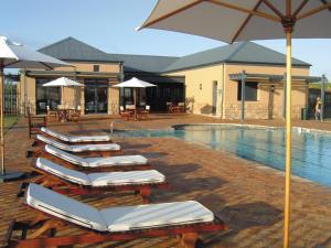 a row of lounge chairs with umbrellas next to a pool at The Lodge at Atlantic Beach in Melkbosstrand