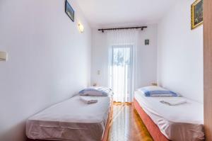 two beds in a room with a window at Apartment Jasna summer barbeque in Srima