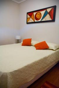 1 dormitorio con 1 cama con almohadas de color naranja en Petit Apart Villa Regina en Villa Regina