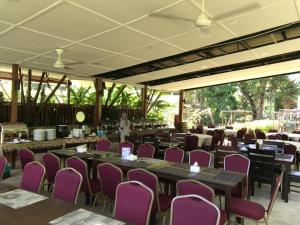 um salão de banquetes com mesas e cadeiras roxas em Nature Lodge Sepilok em Sepilok