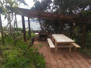 una mesa de picnic y un banco bajo una pérgola en Alojha Coliumo Dichato, en Coliumo