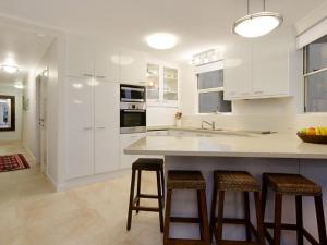 a kitchen with white cabinets and bar stools at Mariner Cove 1 in Mooloolaba