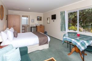 um quarto de hotel com uma cama, uma mesa e uma janela em Breakaway Bed & Breakfast em Coromandel Town