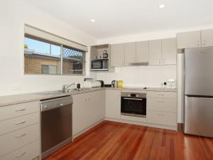 a kitchen with white cabinets and stainless steel appliances at Oloway 40 in Alexandra Headland