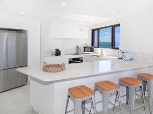 a white kitchen with a counter and stools at Parkyn Place 7 in Mooloolaba