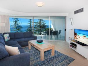 a living room with a couch and a tv and a table at Sirocco 506 in Mooloolaba