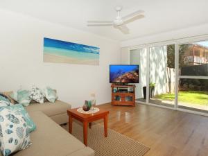 uma sala de estar com um sofá e uma televisão de ecrã plano em Toorumbee 4 38 em Mooloolaba