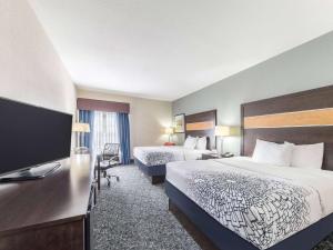 a hotel room with two beds and a flat screen tv at La Quinta by Wyndham Tulsa - Catoosa in Catoosa