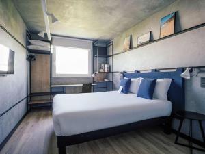 ein Schlafzimmer mit einem großen Bett mit blauen und weißen Kissen in der Unterkunft Ibis Barcelona Castelldefels in Castelldefels