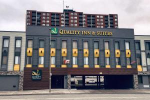 un edificio con una posada universitaria y suites firmando en él en Quality Inn & Suites Downtown Windsor, ON, Canada en Windsor