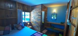 Bong's Guesthouse M'Pai Bay في كوه رونغ ساملوم: غرفة نوم بسرير ازرق وجدار من الطوب