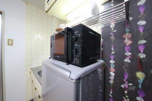 y baño con microondas y nevera. en EX Tenjinnomori Apartment 104, en Osaka