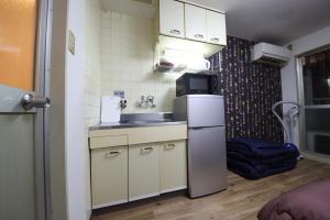 una pequeña cocina con fregadero y nevera. en EX Tenjinnomori Apartment 104, en Osaka